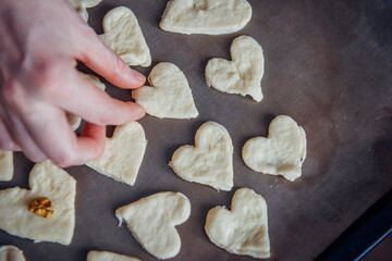 Raw homemade heart-shaped cookies on a baking sheet. Concept of fresh pastry, surprise for Valentine's day.