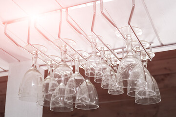 Clear wine glasses hanging in a row over bar rack