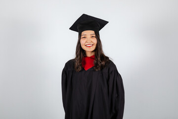 Smiling graduate student in mortarboard and bachelor gown on white background
