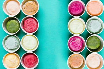 Top view of Ice cream flavors in cup and topping on green table background, sweet and dessert food concept