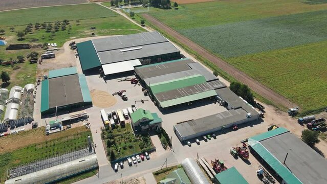 Aerial drone footage of the farm buildings angar near the multicolored fields