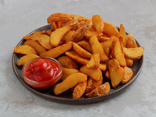Baked potato wedges. Mexican potatoes. Potatoes with paprika and sauce. Selective focus. On a round dish. Light background. Close-up.