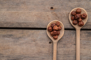 shelled hazelnuts in spoon on wooden background, close up