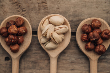 Wooden spoons with hazelnuts and  pistachios isolated on wooden background.