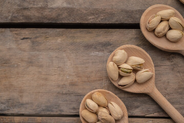 Pistachios in a wooden spoon. On a wooden background. Top view