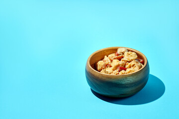 Stewed potatoes with meat and mushrooms in a wooden bowl on a blue background