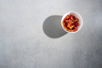 dried tomatoes with spices in a white plate on a gray concrete background
