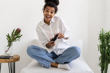 Cheerful afro american woman playing videogame with joystick © brizmaker