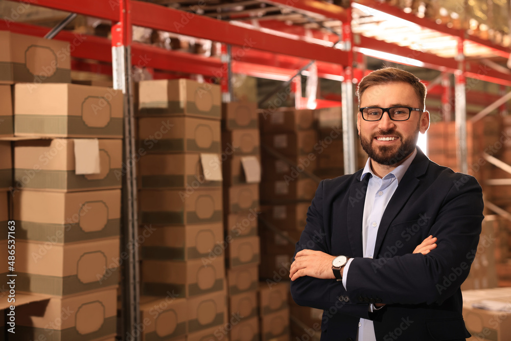 Poster Manager near stacked boxes at warehouse. Logistic center