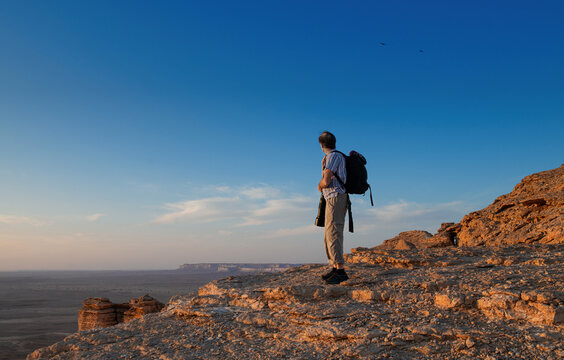 Fototapeta Man standing in desert holding a camera with a telephoto lens, Saudi Arabia