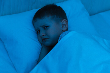 Offended child under a blanket going to bed. Disappointment and emotionality. Afraid of nightmares...