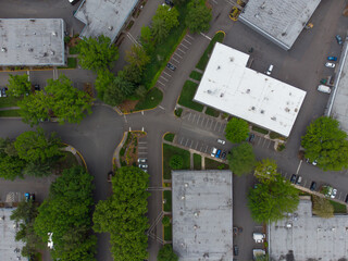 Shooting from the air. Asphalted area, roofs of one-story industrial buildings, car parking. Lots of greenery. Environmental protection, infrastructure, travel, Design, engineering.