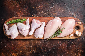 Raw chicken meat, assortment of parts - drumstick, breast fillet, wings, thigh with spices. Dark background. Top view