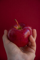 A red healthy apple held against a red background