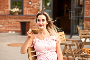 Beautiful woman drinking coffee in a cafe and eating croissant