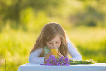 girl drinking juice sitting at the table in nature