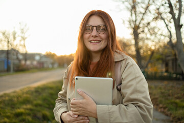 Young beautiful caucasian woman hand holding digital tablet PC in autumn nature at sunset, online