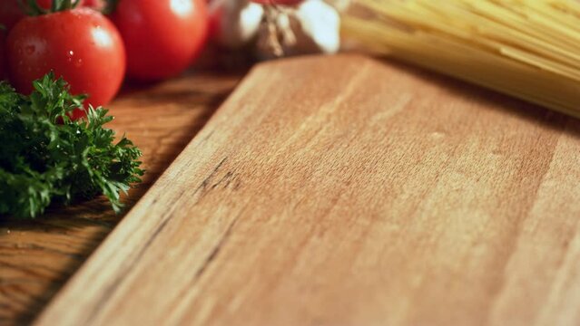 A wooden table with parsley and tomatoes around it.Creative people can put whatever product they want on the floor. Top shot.