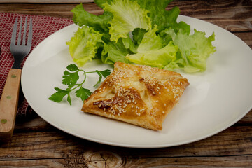 puff pastry with sesame seeds in a white plate with salad 