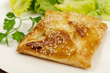 puff pastry with sesame seeds in a white plate with salad 