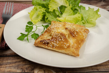 puff pastry with sesame seeds in a white plate with salad 