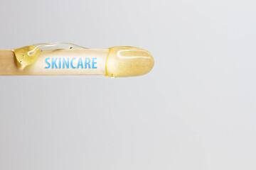 The inscription skincare on a wooden spatula with wax for hair removal.