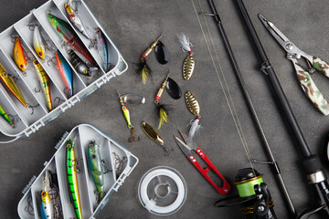 Fishing tackle - fishing spinning rod, hooks and lures on gray background. Active hobby recreation...
