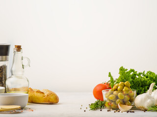 Green olives, vegetables, herbs, spices on a white background. Ingredients for making salads. Vegetarian and diet food, vitamins, detox. There is an empty space for an inscription.