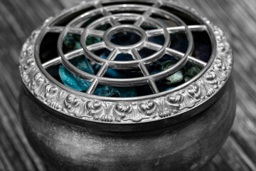 Potpourri in a vintage silver decorated bowl on a wood background.  With selective colour