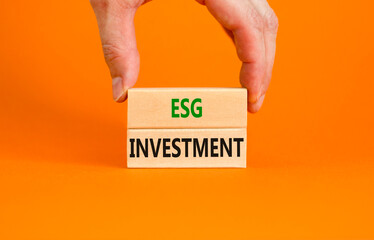 ESG environmental social governance investment symbol. Concept words ESG investment on blocks on a beautiful orange background. Businessman hand. Business, ESG investment concept. Copy space.