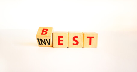 Best invest symbol. Turned wooden cubes and changed the word Invest to Best. Beautiful white table, white background. Business and best invest concept. Copy space.