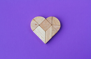 Wooden heart puzzle on purple background