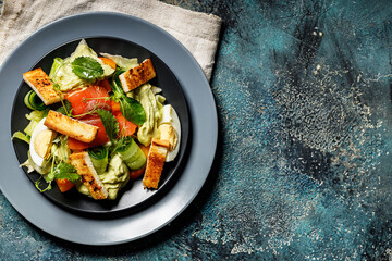 Delicious green salad with salmon, vegetables and croutons.Mediterranean Kitchen. Healthy diet. Top view. Copy space