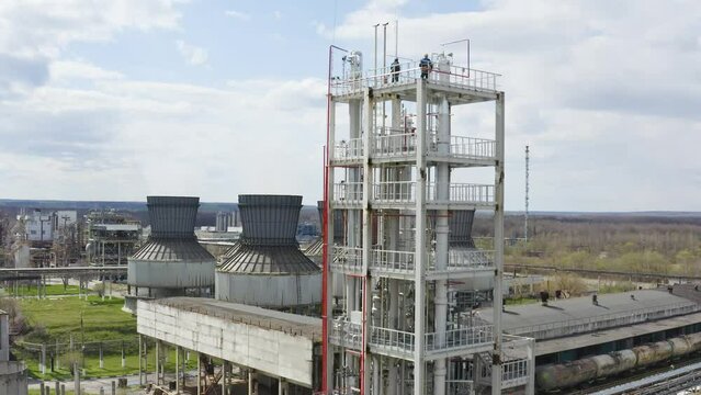 Engineers stand on the large industrial building. Industrial pipes of plant chimney smoke. Chemical Plant ejects a cloud of steam. Environmental pollution. Chemical emissions into the atmosphere. 