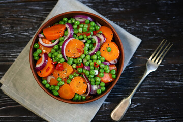 Healthy salad with carrots, green peas and blue onions. Vegan diet.