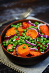 Healthy salad with carrots, green peas and blue onions. Vegan diet.