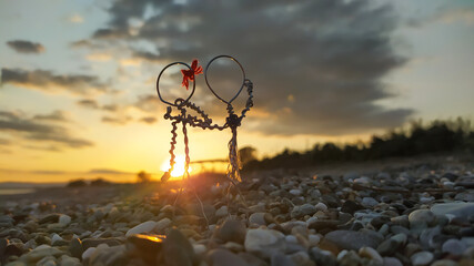 wire figures of couple hugging while watching the sunset on the beach