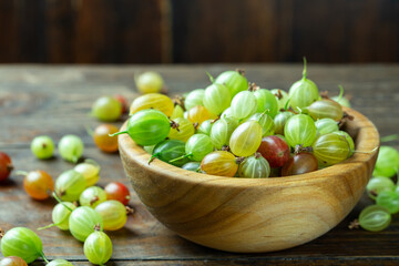 Ripe gooseberry in a wood plate, place for text, top view