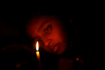 girl looking on a candle flame in contemplation and sad mood