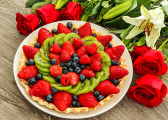 Cake with berries on a plate and flowers for 14 valentine's day. Strawberries, blackberries, kiwi and raspberries 
