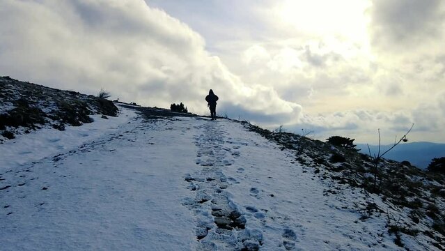 Silhouette hiker man walking towards cloudy sky on mountain in winter. slow motion video