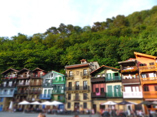 Fototapeta na wymiar Plaza de Santiago, in the town of Pasajes, (Pasaia). Traditional houses with facades of different colors and wooden balconies. In the background leafy trees. San Sebastian, Guipuzcoa, Basque Country.