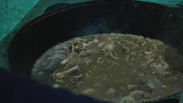Cook stirs meat and onio in boiling water. Cooking for bog asian family.