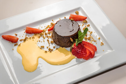 Bunet pudding,traditional italian Piedmont dessert in white plate with strawberries and eggnog