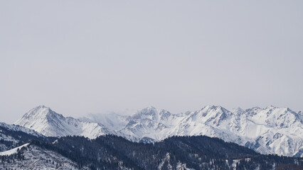 Fototapeta na wymiar Misty snowy mountain peaks on a cloudy day