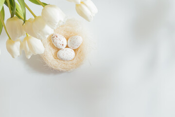 Flat lay easter composition with white tulips in a vase and easter eggs on a light background