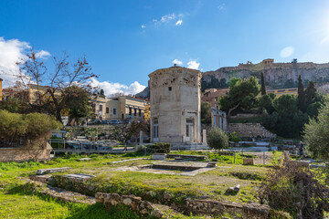 Fototapeta na wymiar ATHENS, GREECE - DECEMBER 19, 2021: Roman Agora with ancient columns and Wind tower with blue sky.
