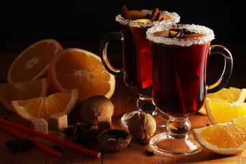 Two cups with ready mulled wine with anise, cinnamon and nuts around	
