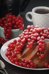 A cake with fresh red currant and tea	