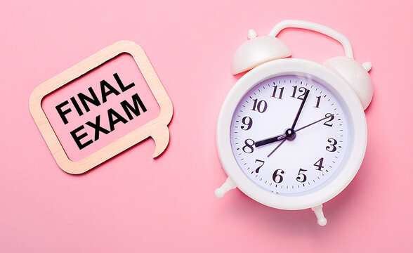 On a delicate pink background, a white alarm clock and a wooden frame with the text FINAL EXAM